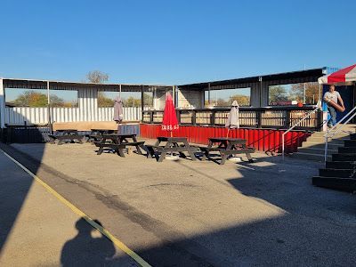 A picnic area with tables and umbrellas in front of a building.