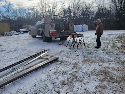 A man is standing in front of a truck in the snow.