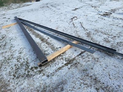 A bunch of metal pieces are laying on the ground in the snow.
