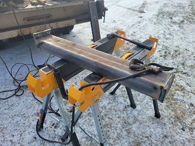 A piece of metal is sitting on top of a workbench in the snow.