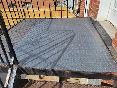 A metal staircase with a brick building in the background.