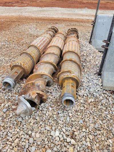 Three metal pipes are sitting on top of a pile of gravel.