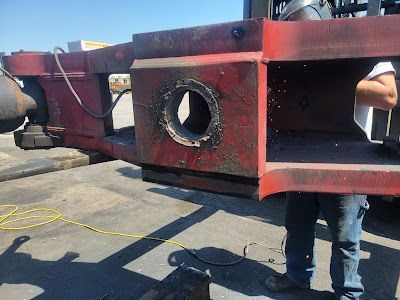 A man is standing next to a large red piece of metal with a hole in it.