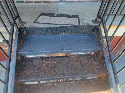 A set of stairs with a welcome mat on the side of them.
