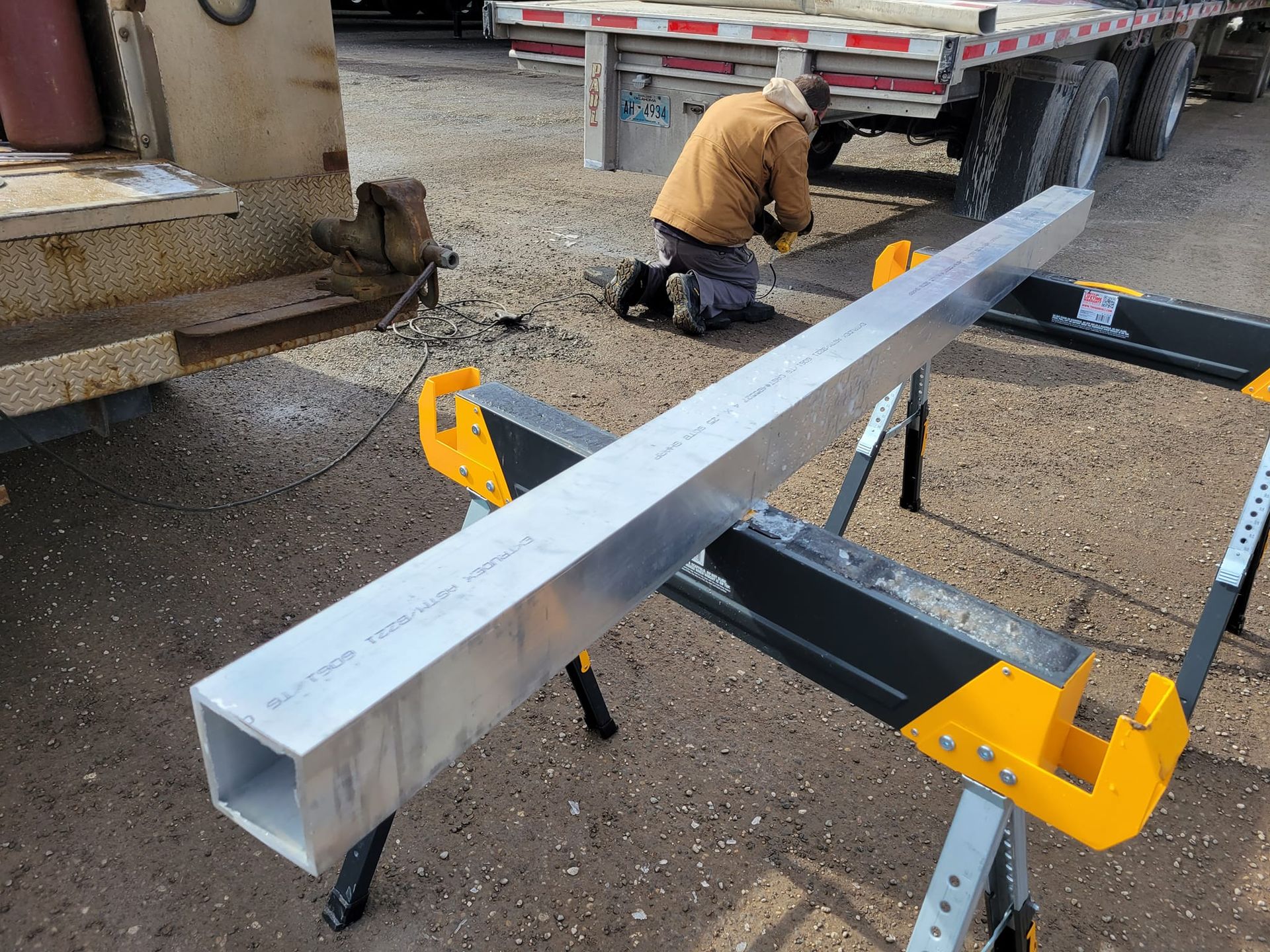 A man is kneeling down next to a large piece of metal