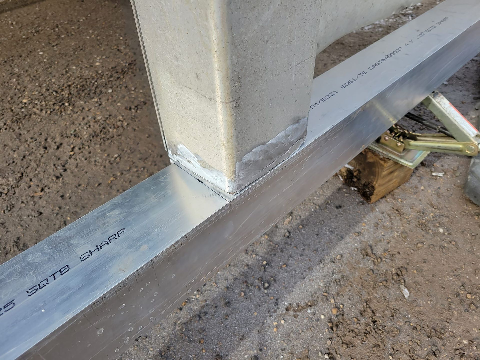 A piece of metal is sitting on the ground next to a concrete post.