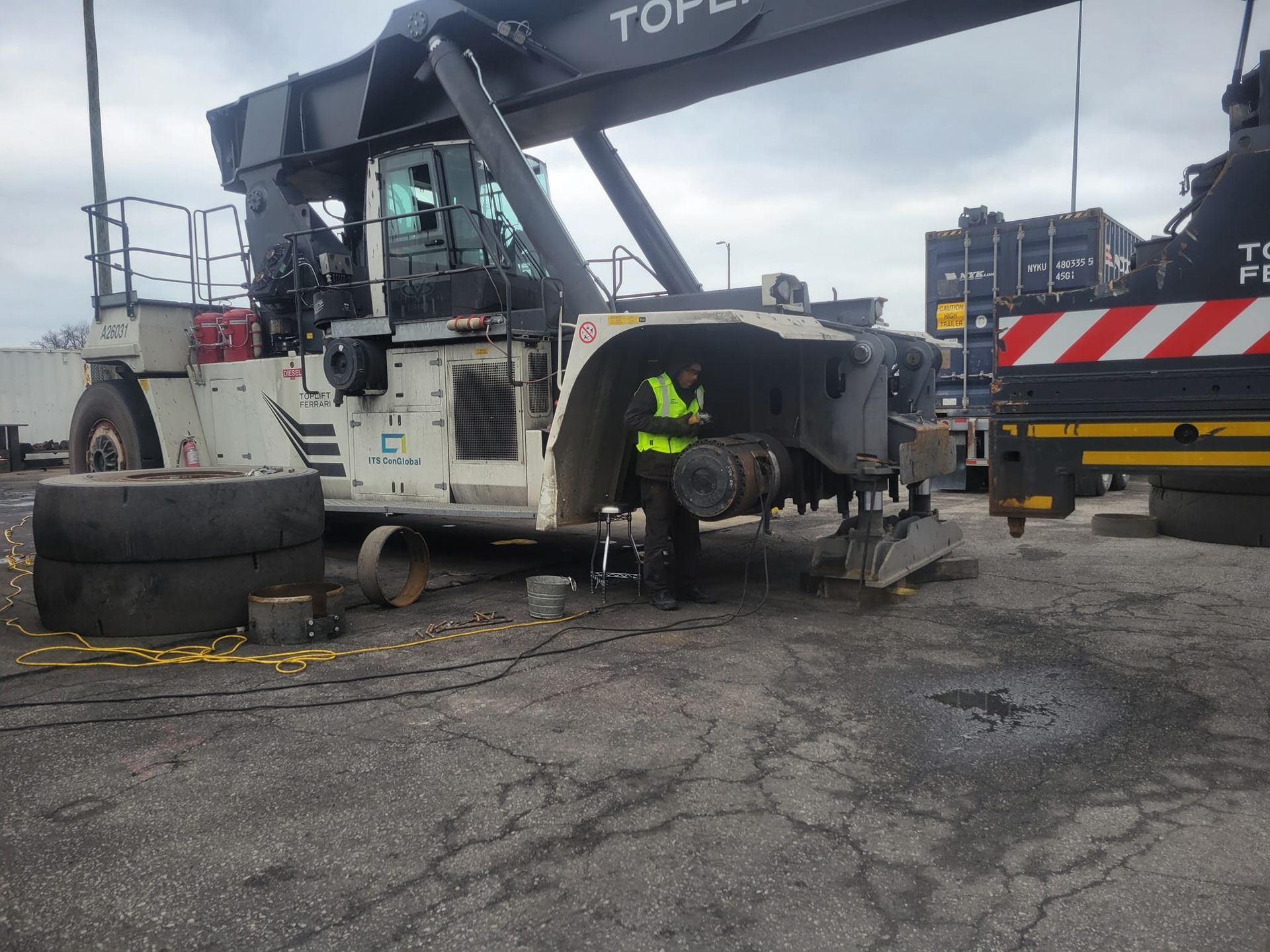 A man in a yellow vest is working on a large crane