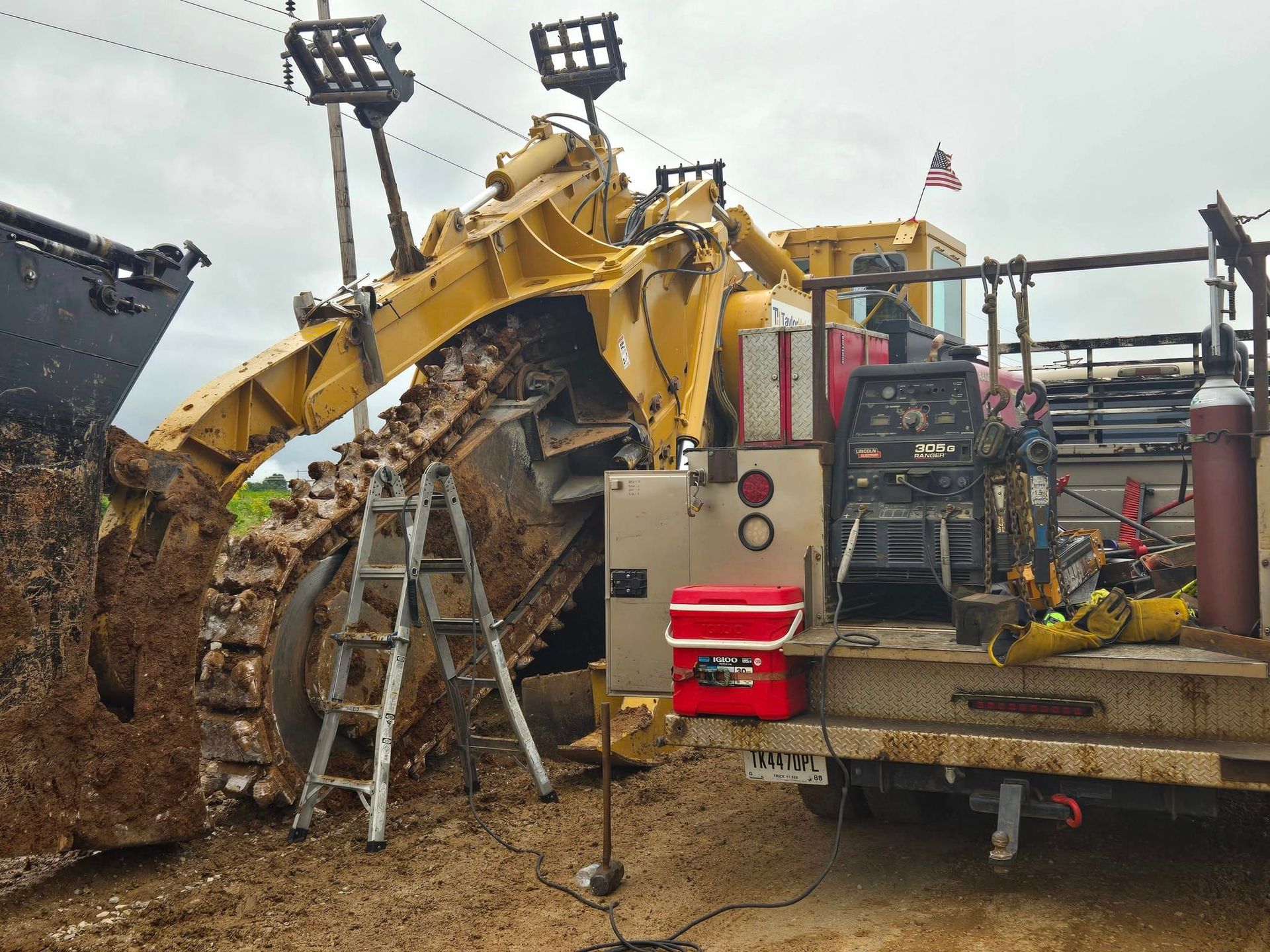 A bulldozer is sitting on top of a truck with a red cooler attached to it.