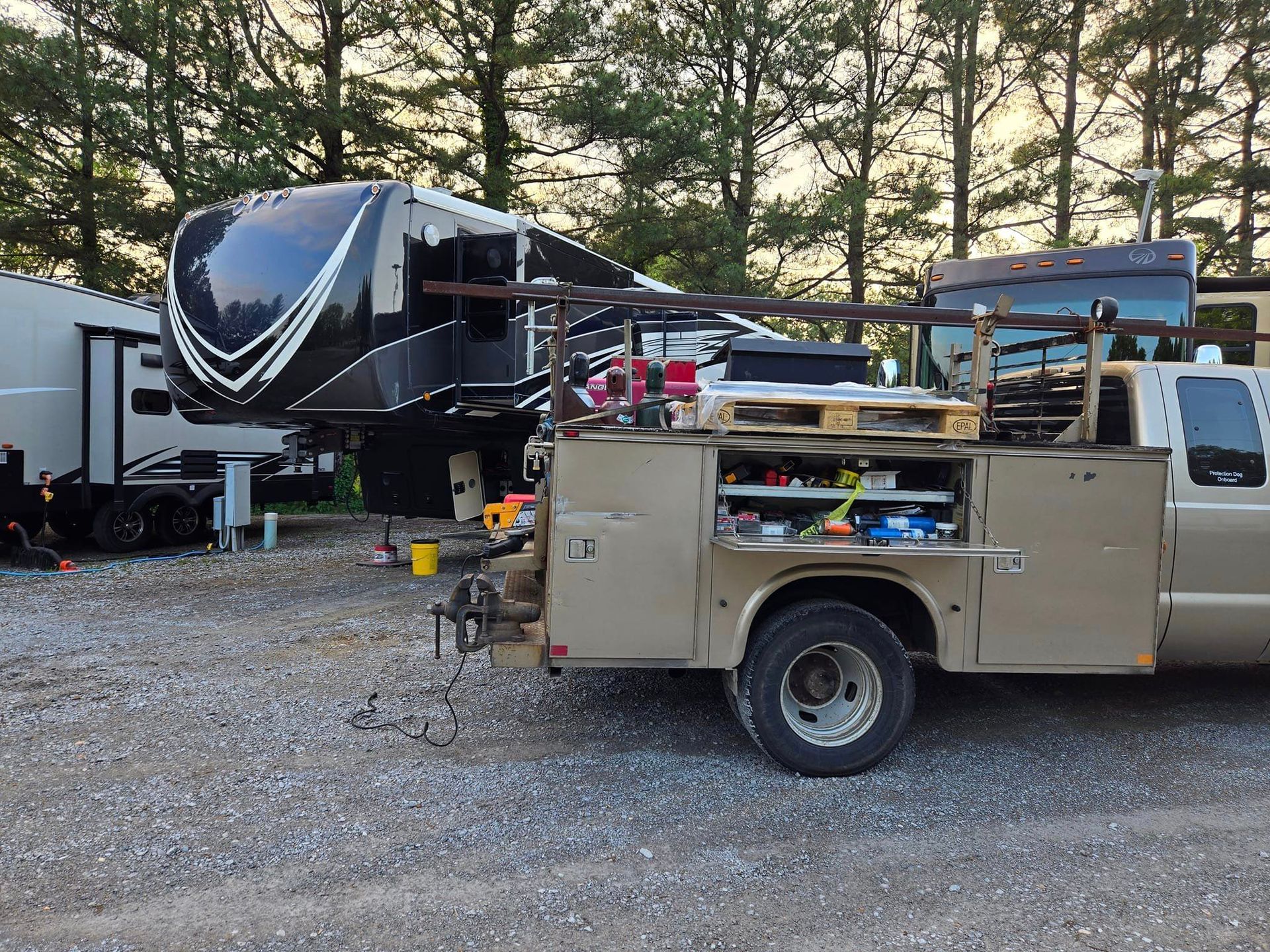 A utility truck is parked next to a rv in a parking lot.