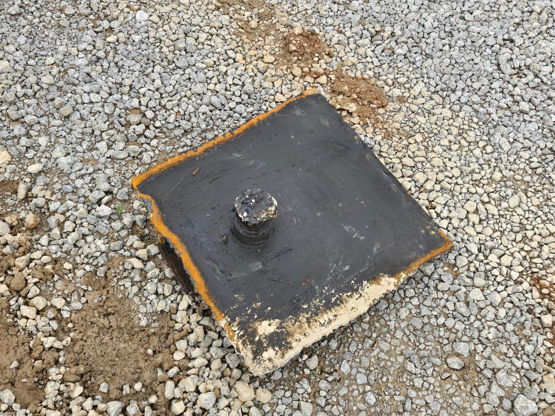 A piece of metal is sitting on top of a pile of gravel.