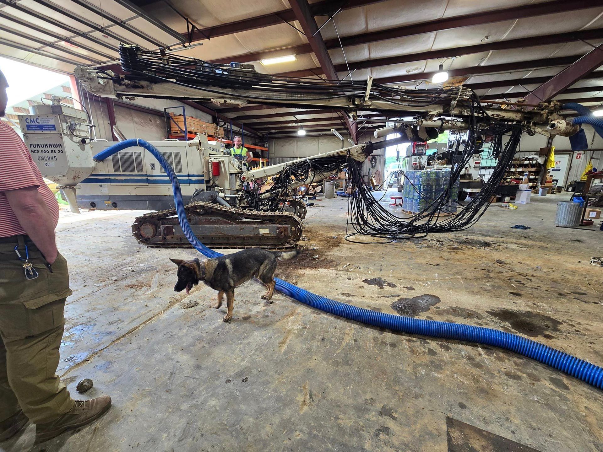 A man and a dog are standing next to a machine in a garage.