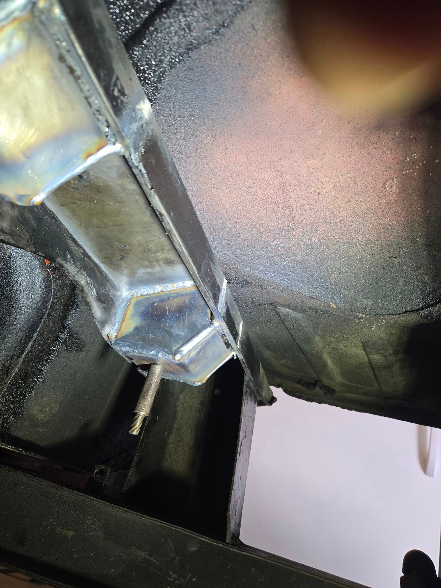 A close up of a metal pipe under a car.