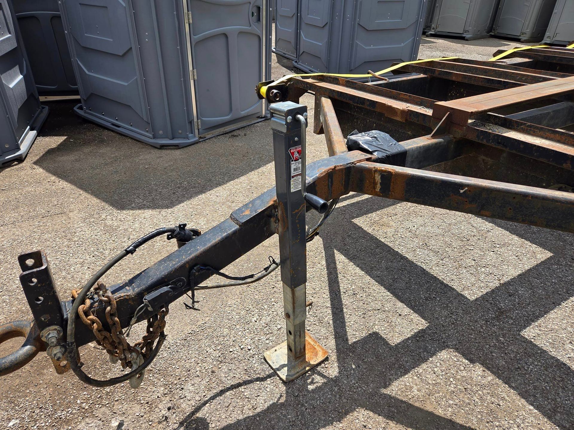 A trailer is sitting on the ground next to a row of portable toilets.