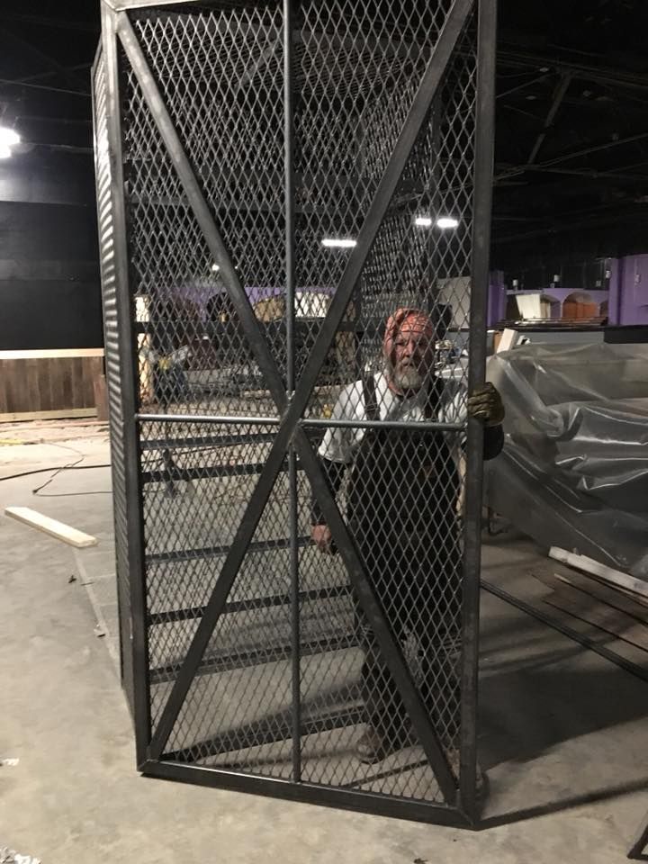 A man with a beard is standing in a metal cage.