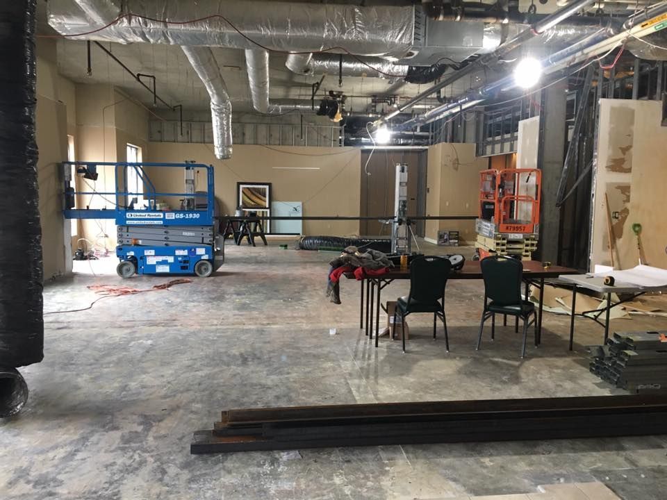 A large room with a table and chairs in it is being remodeled.