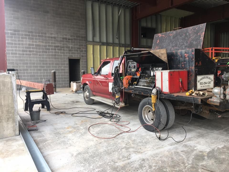 A red truck is parked in a garage next to a brick wall.