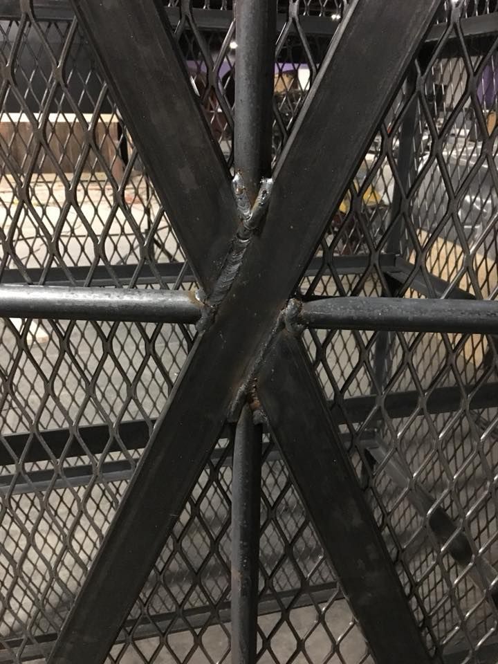 A close up of a metal fence with a cross on it.