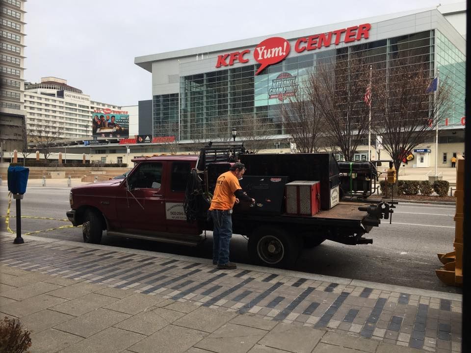 A truck is parked in front of a building that says kfc yum center