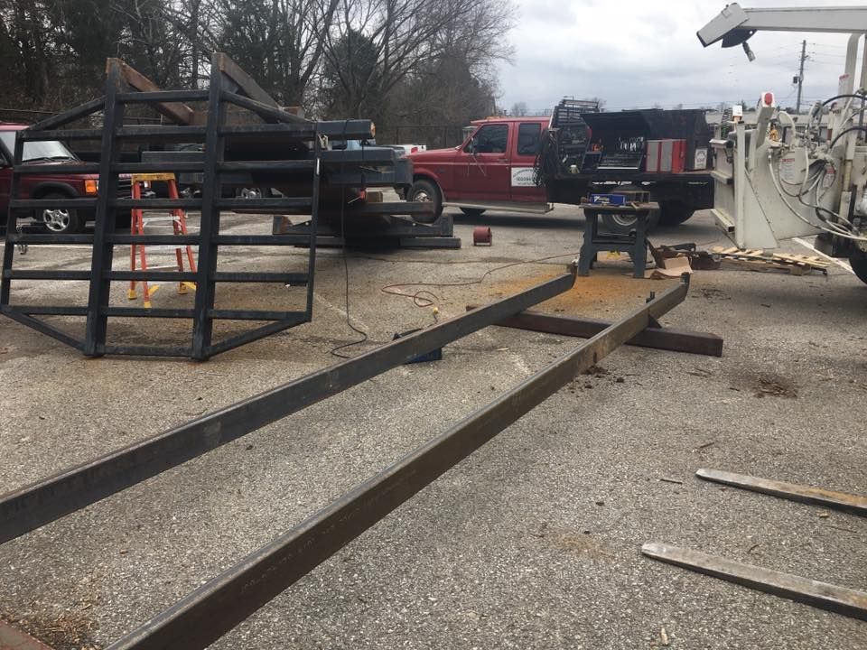 A man is working on a piece of metal in a parking lot.
