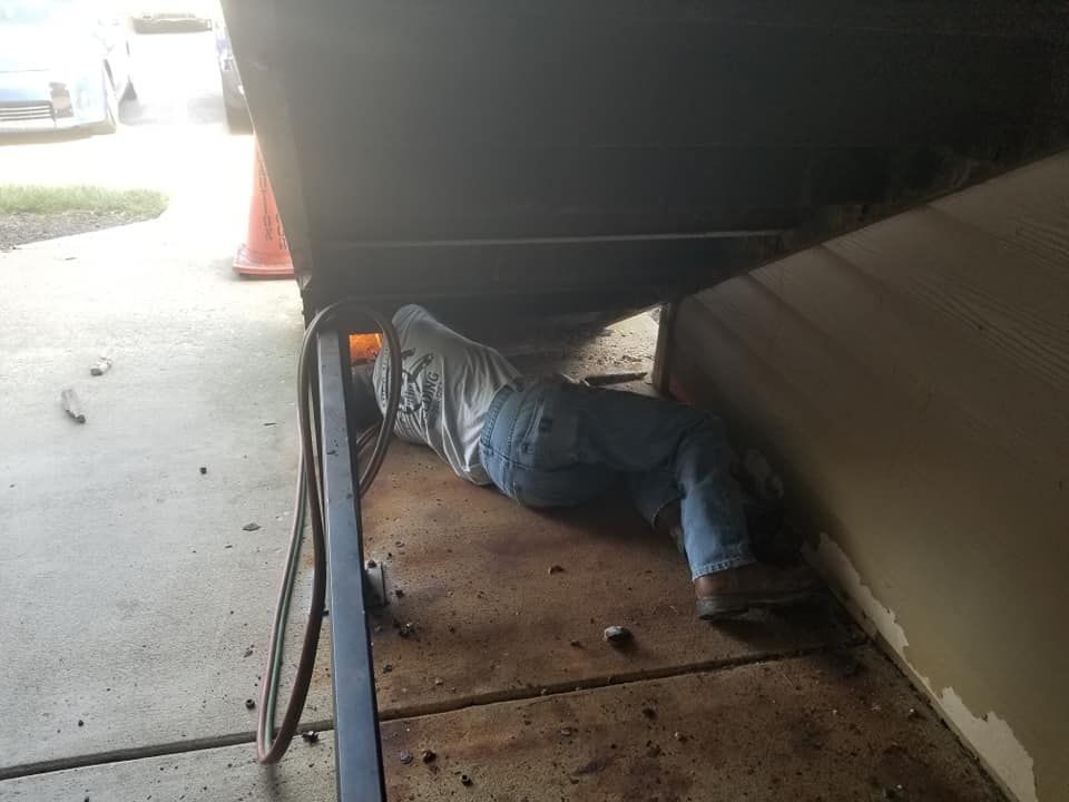 A man is laying under a boat in a garage.