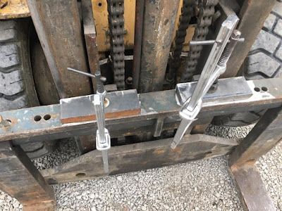 A forklift is sitting on top of a gravel road.