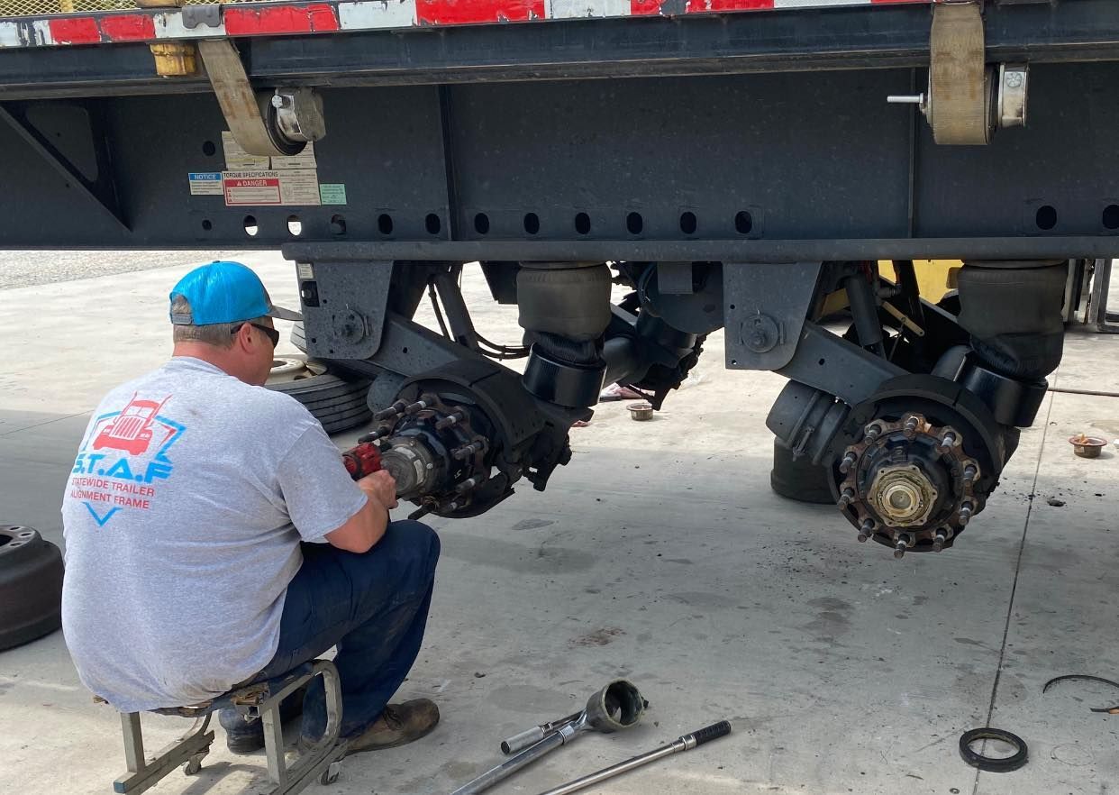 A man in a gray shirt is working on a trailer