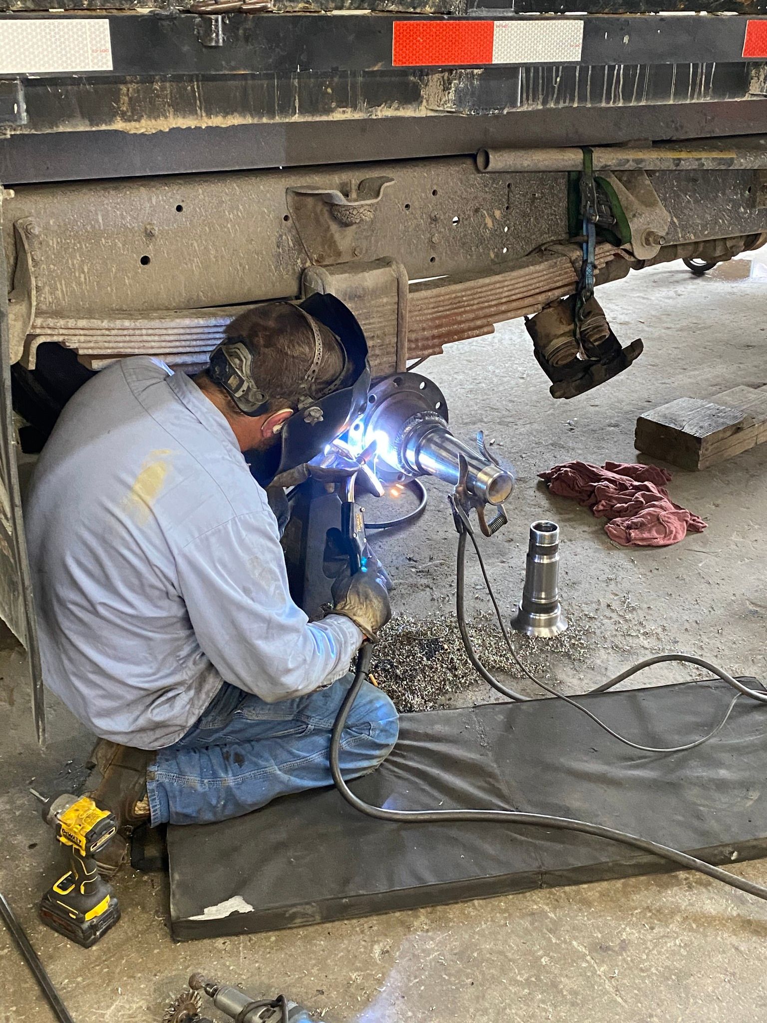 A man is welding under a truck in a garage.