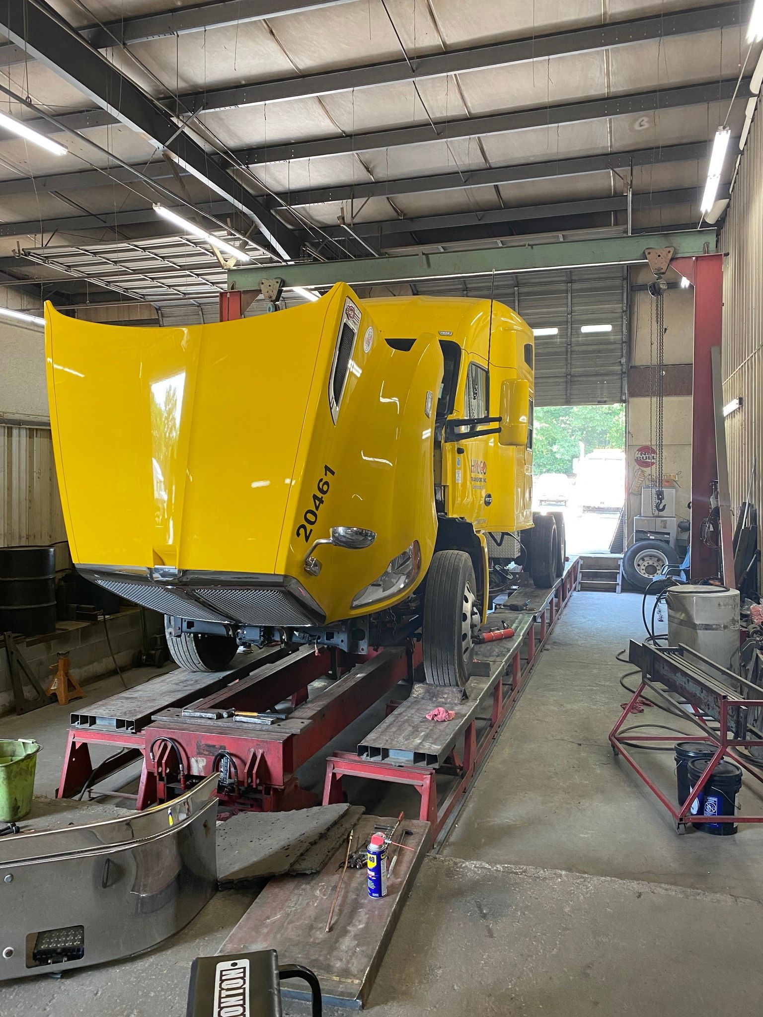 A yellow truck is being repaired in a garage.