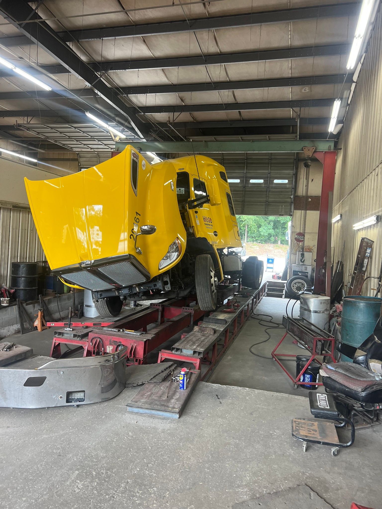 A yellow truck is sitting on a lift in a garage.