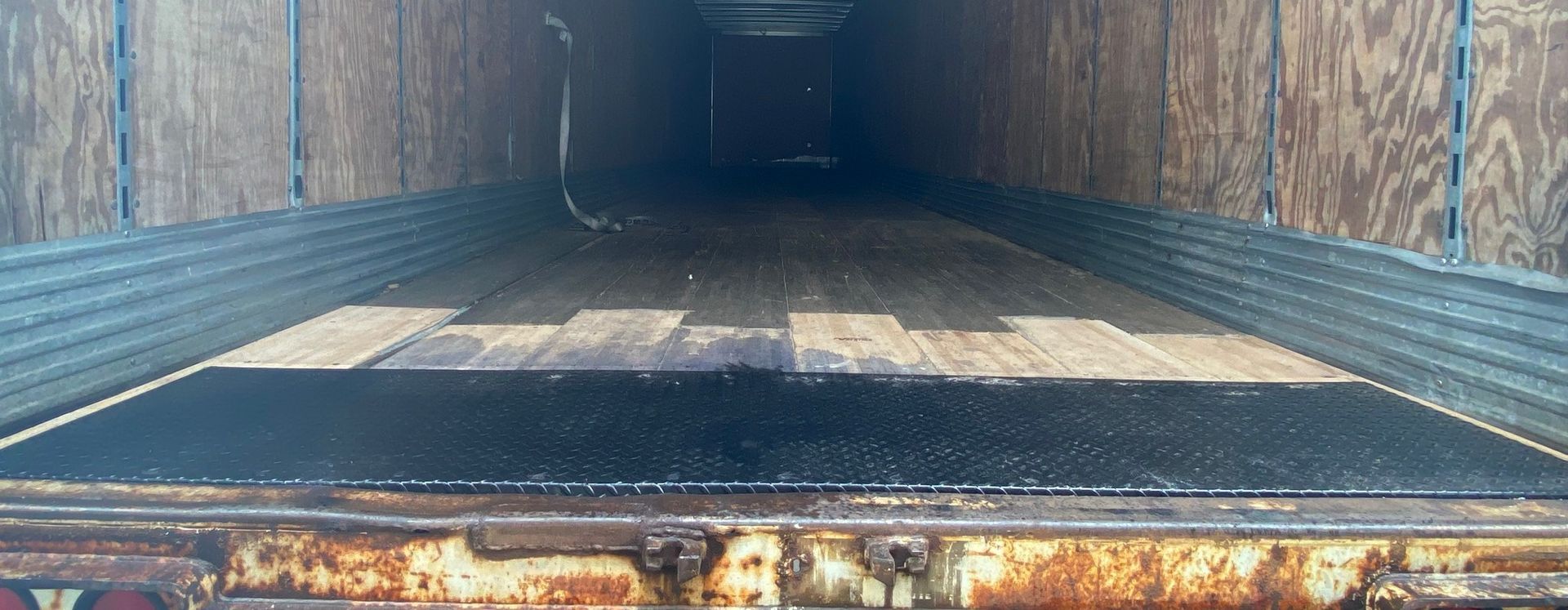 The inside of a trailer with a black mat on the floor.