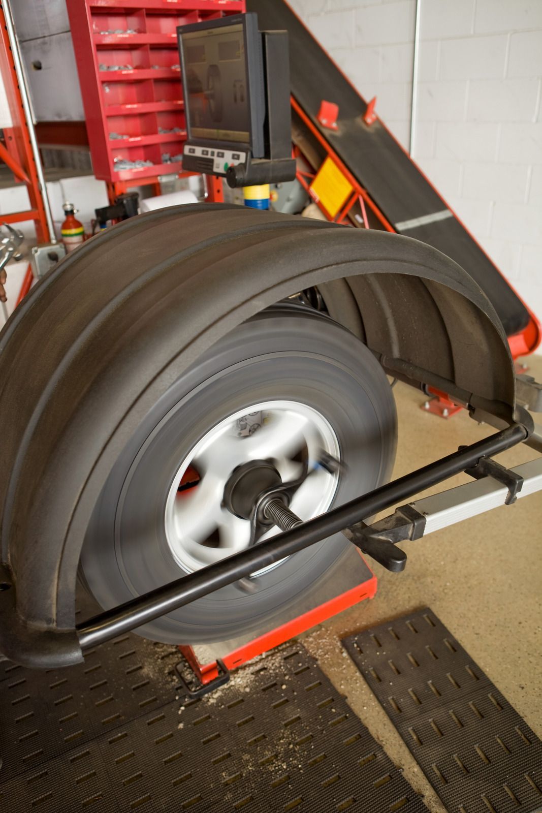 A tire is being balanced on a machine in a garage.