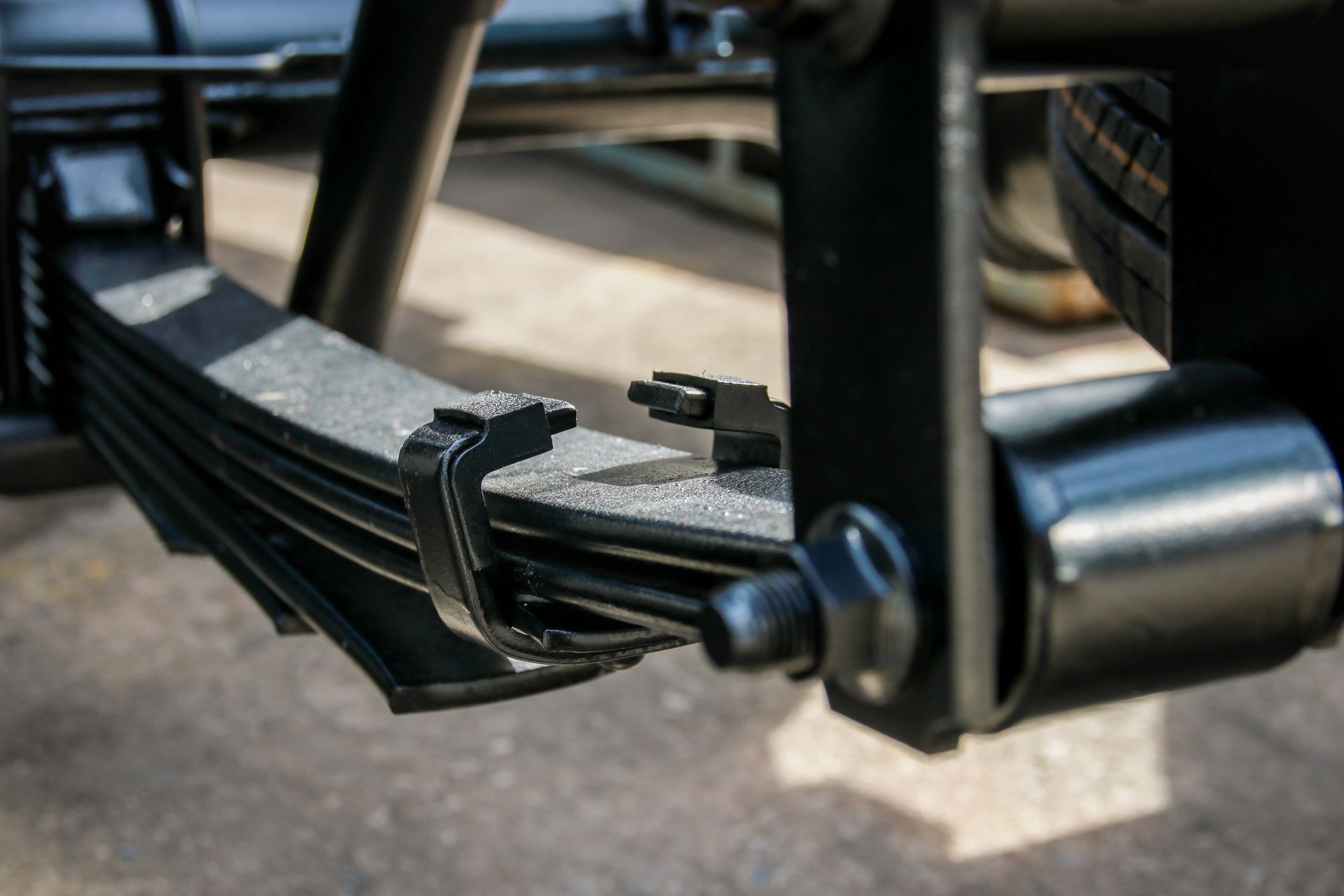 Black leaf spring suspension on a vehicle, detail view.