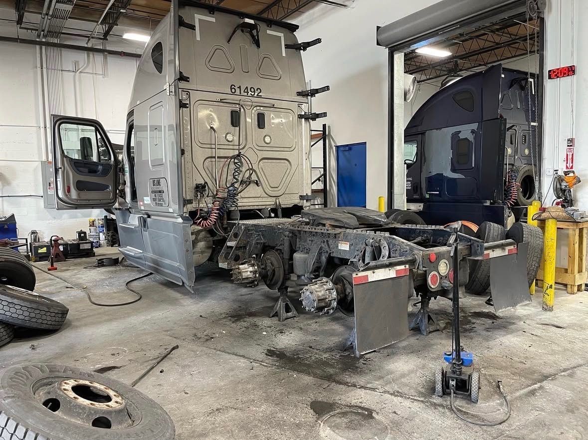 Truck repair shop: Partially disassembled semi-truck in a garage with tools and parts visible.