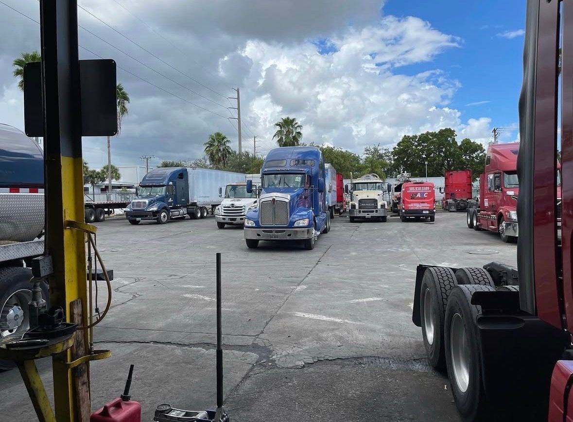 Semi-trucks parked in a lot under a partly cloudy sky.