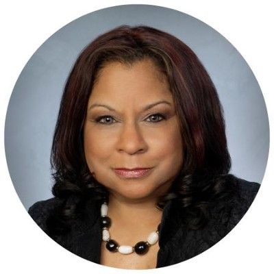 A woman is wearing a white jacket and a brown sweater. A woman is wearing a white jacket and a brown sweater.