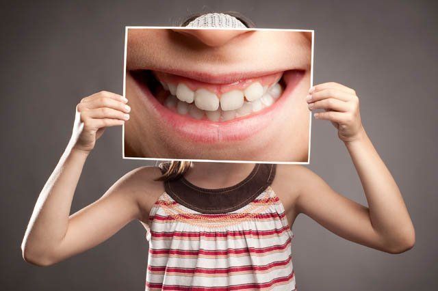 girl holding enlarged comic smile picture in front of face