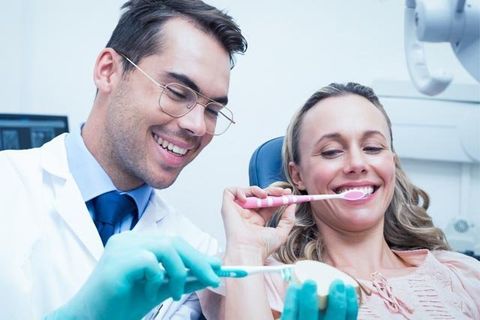 dentist showing woman how to correctly brush teeth