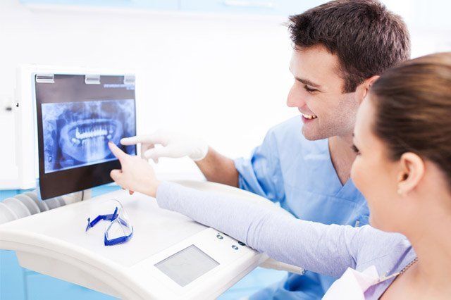 dentist looking at scan of teeth on monitor with patient