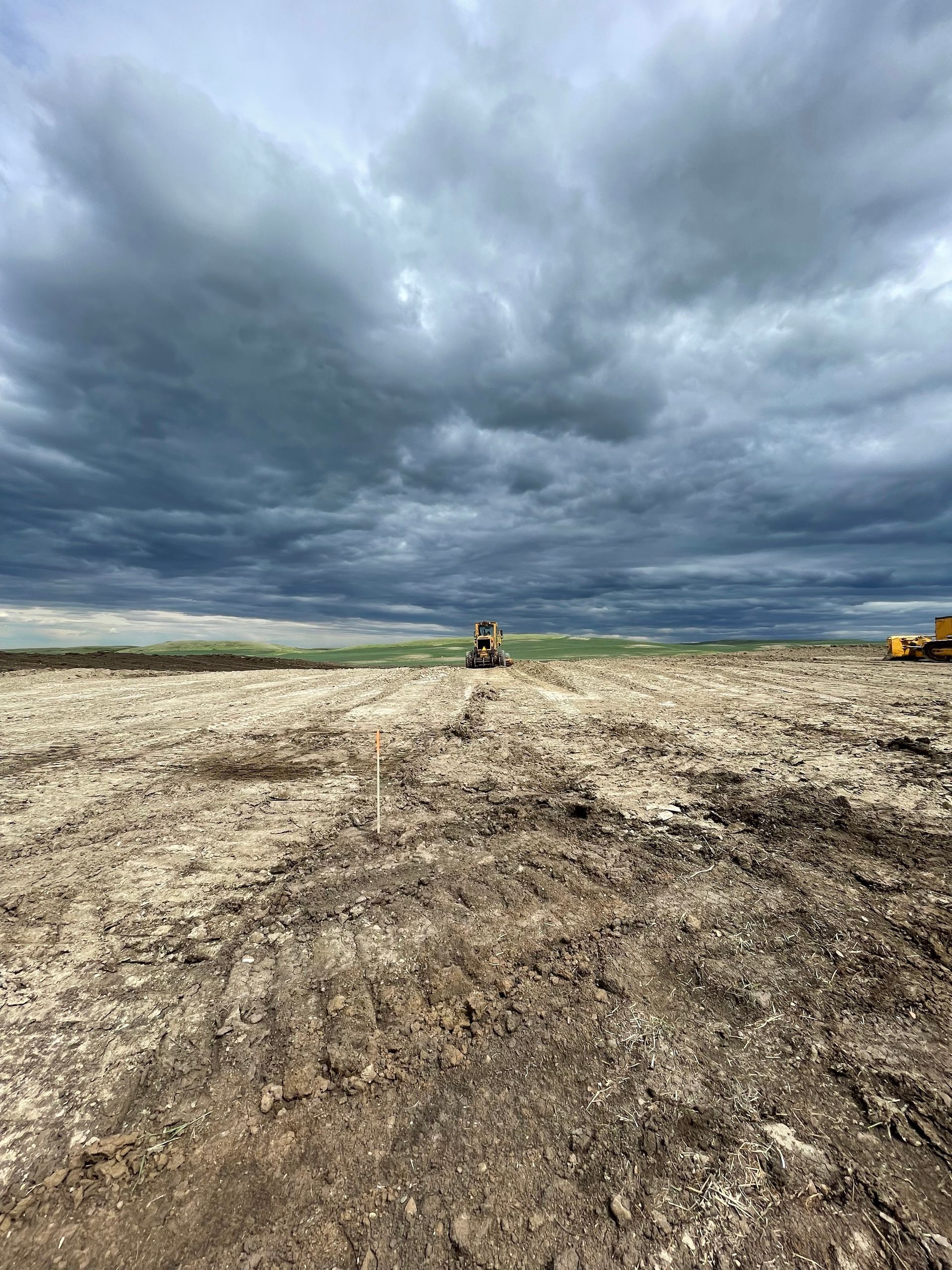 A tractor is plowing a field with a cloudy sky in the background.