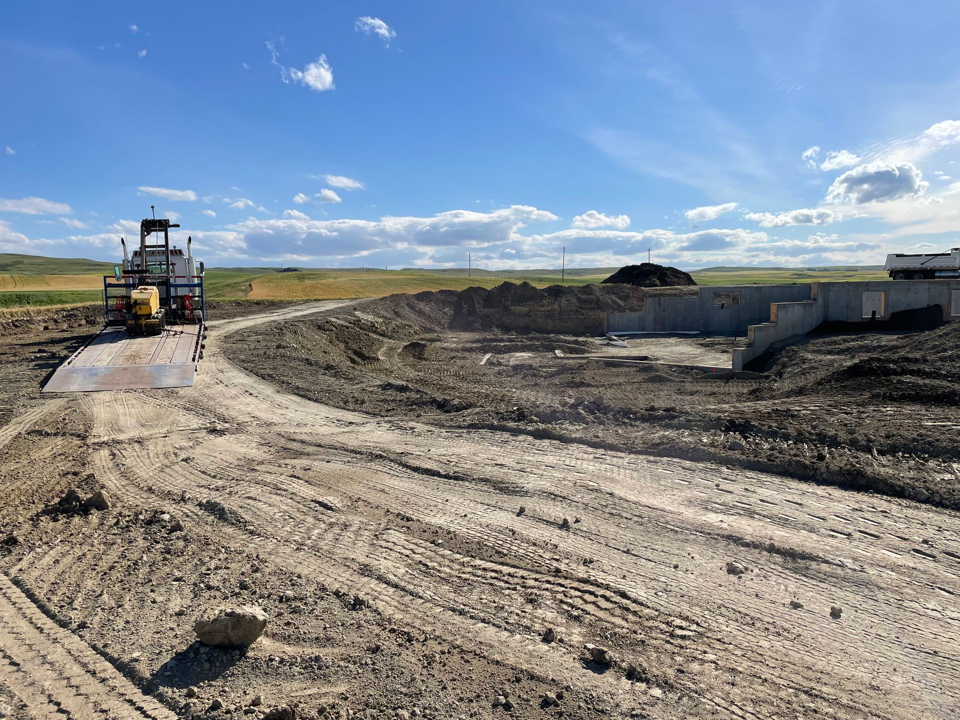 A large dirt road with a bulldozer in the middle of it.