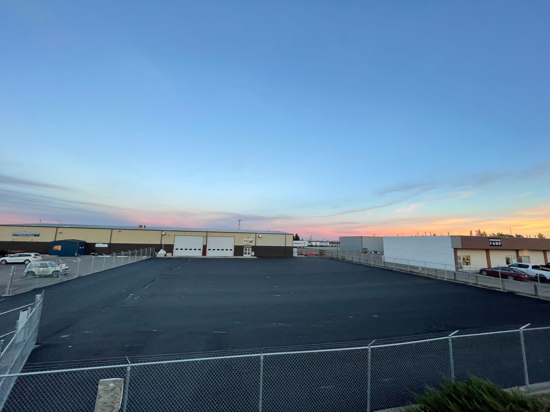 A large empty parking lot surrounded by a chain link fence.