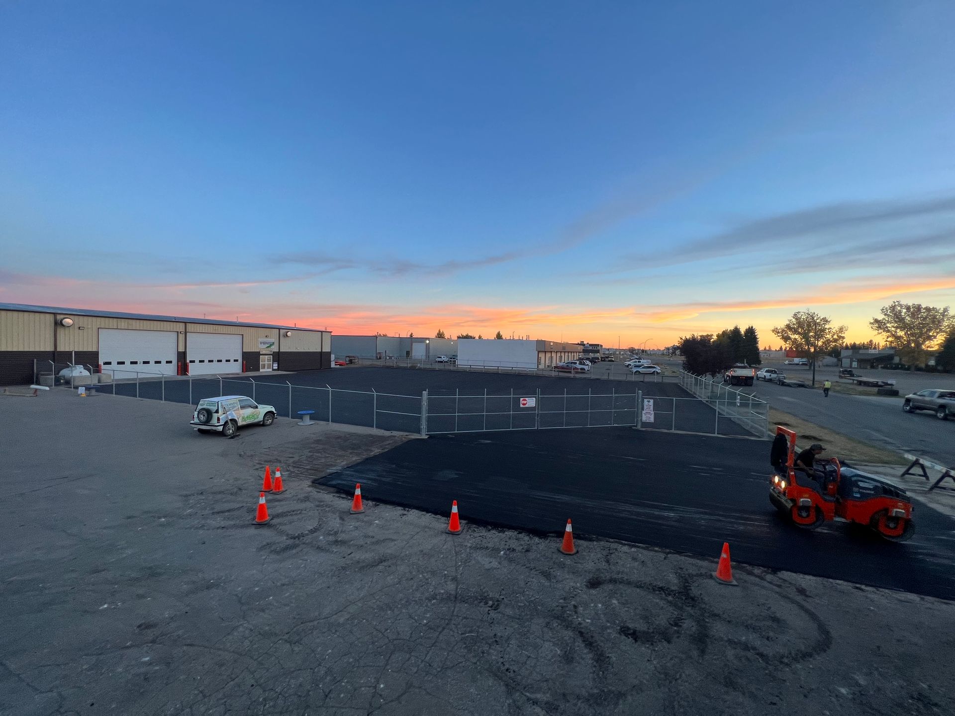 A motorcycle is parked in a parking lot at sunset.