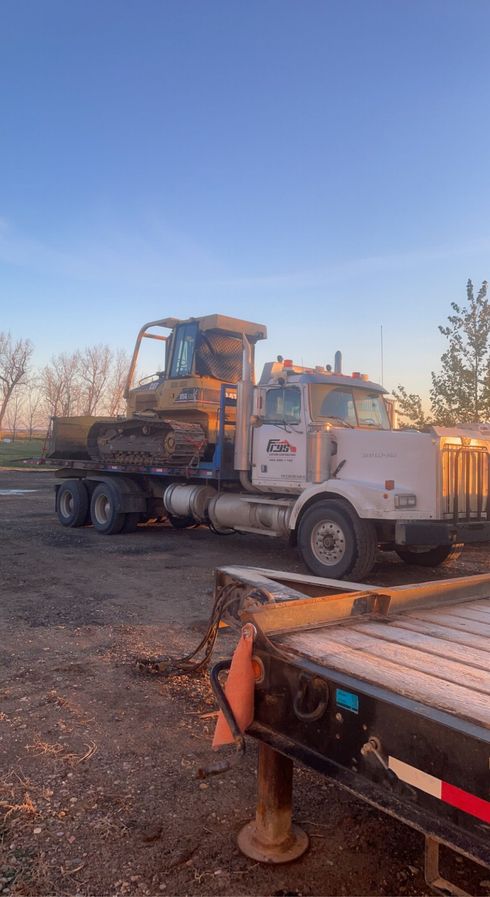 A truck is towing a bulldozer on a trailer.