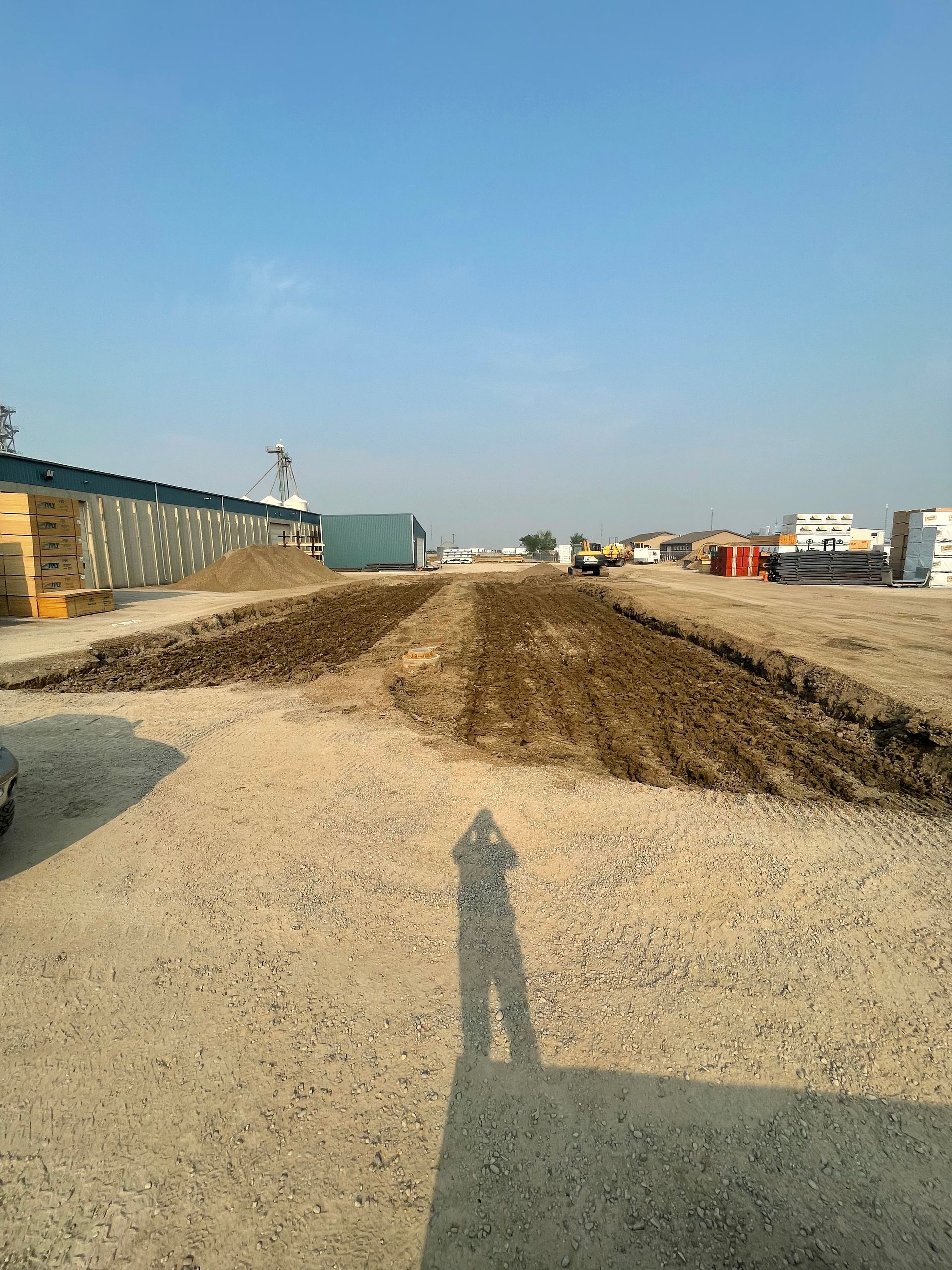 A shadow of a person is cast on a gravel road.