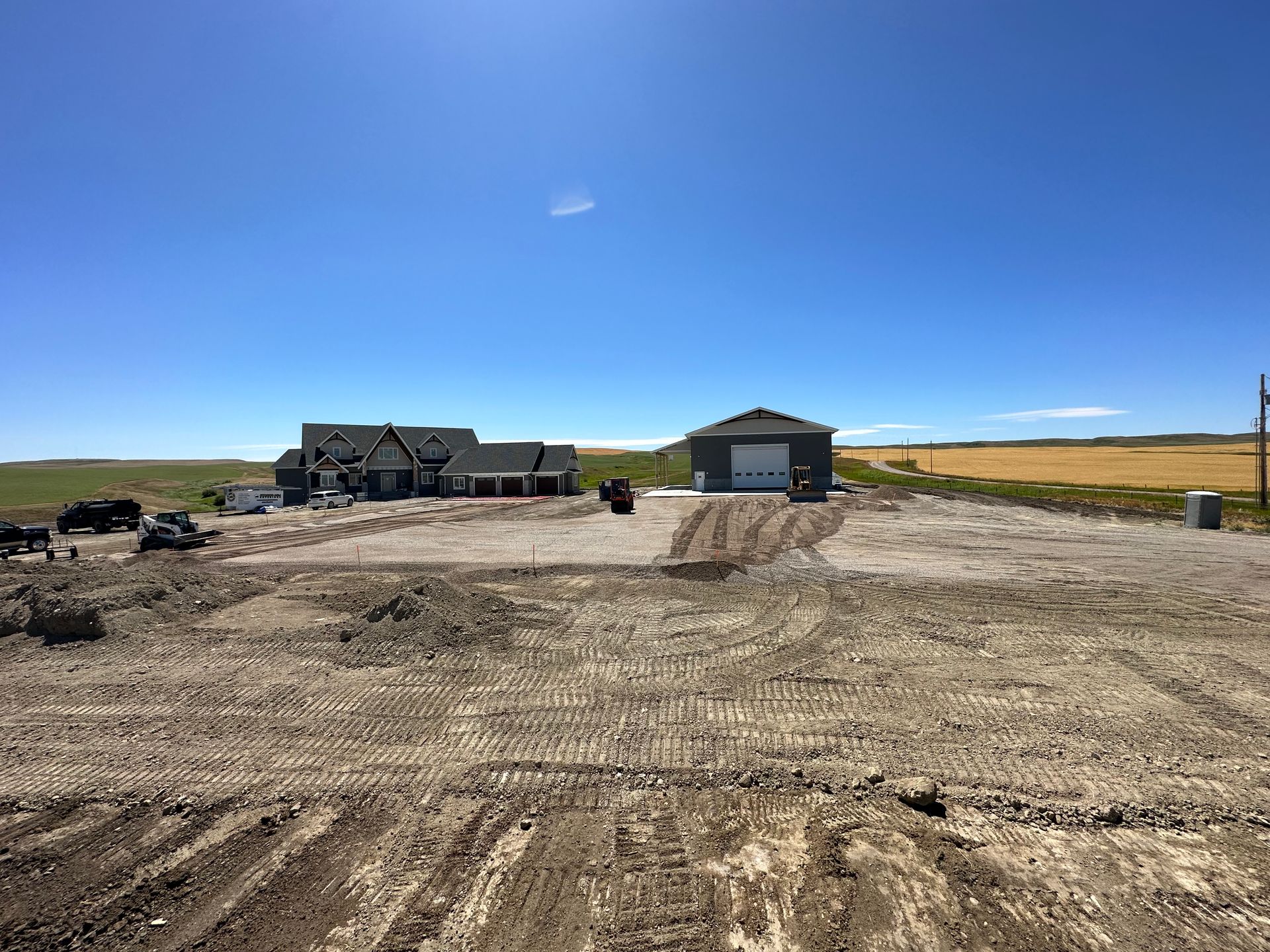A large house is sitting in the middle of a dirt field.