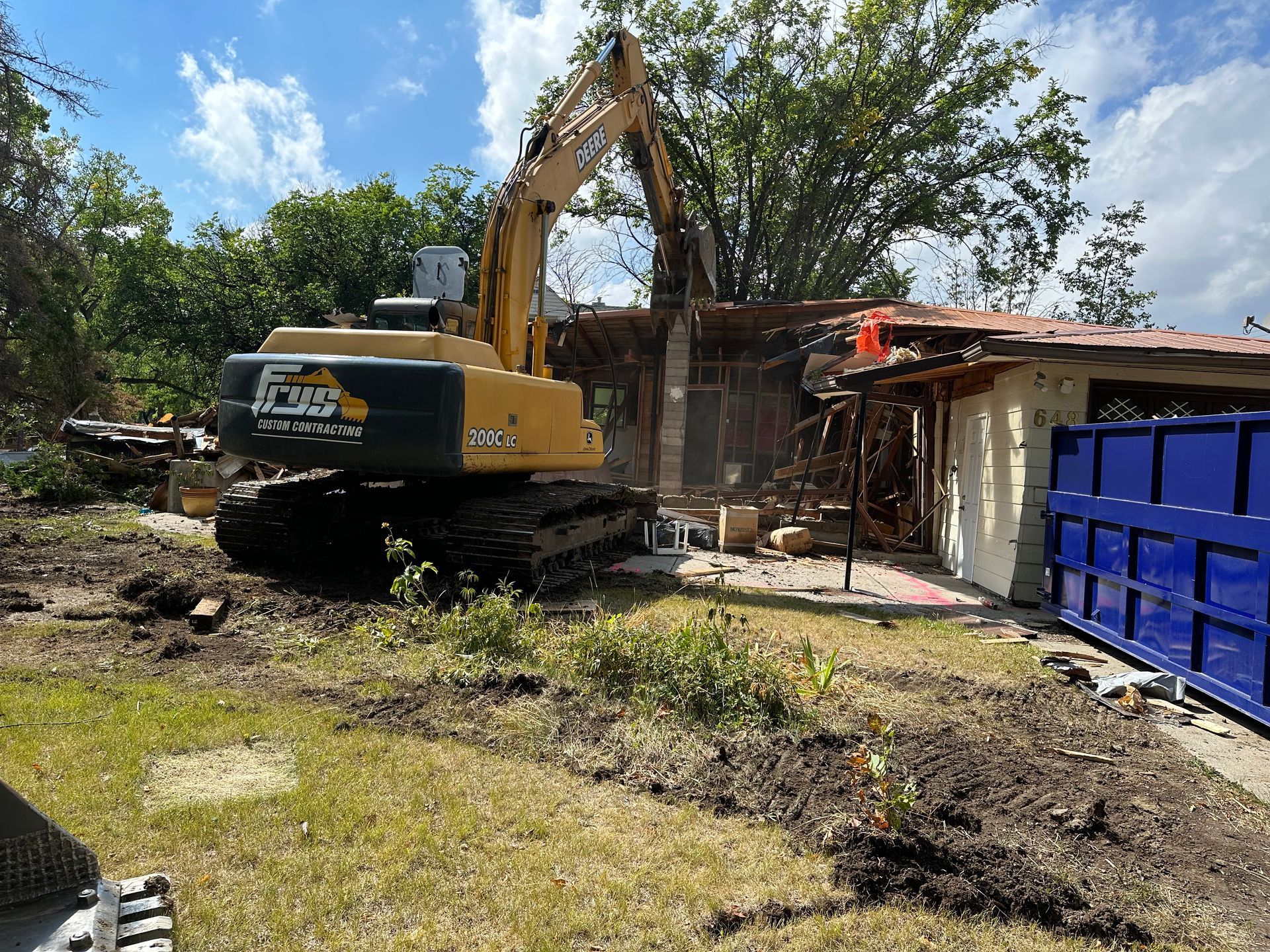 An excavator is demolishing a house in a yard.