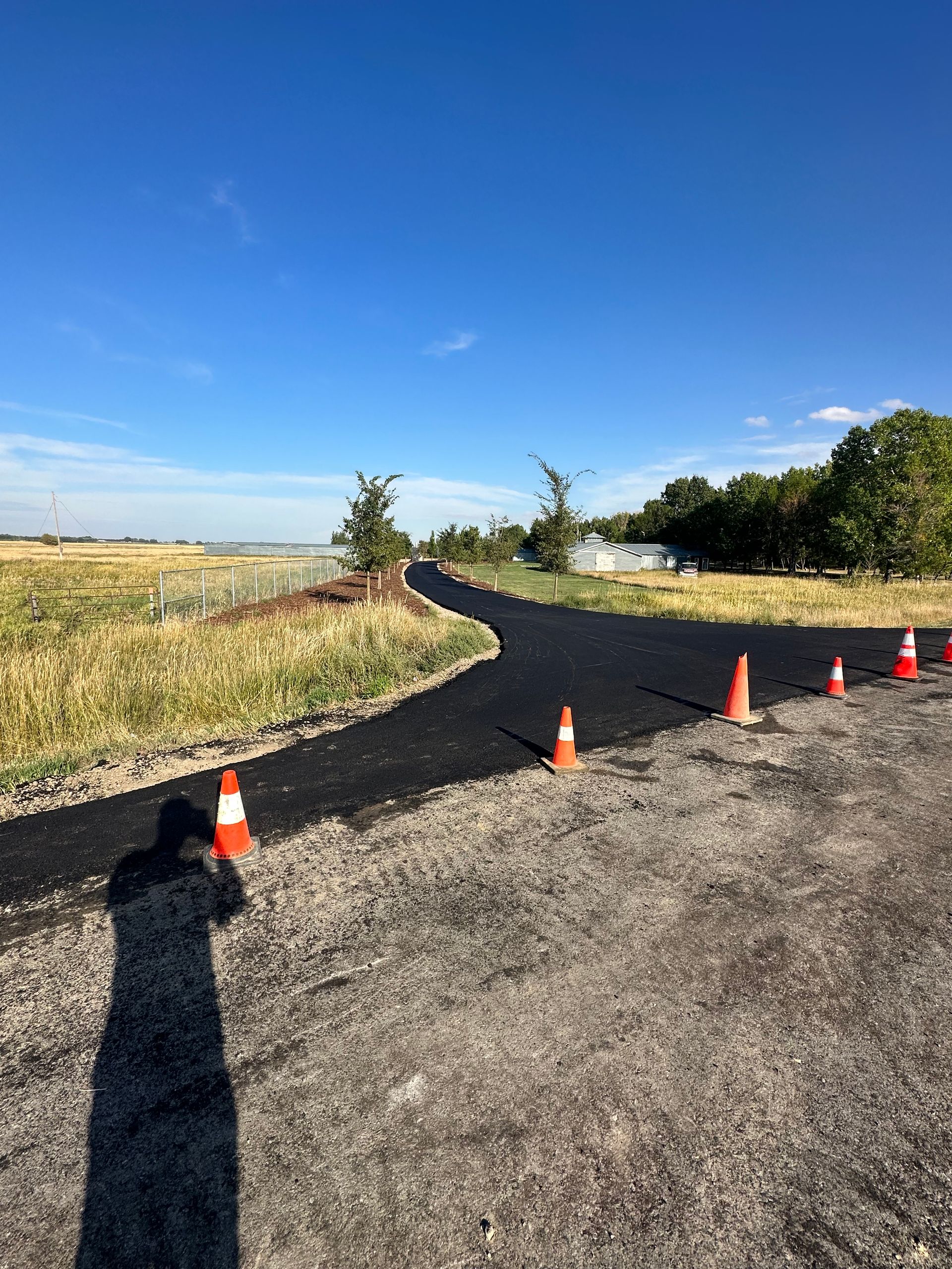 A person is standing on the side of a road with traffic cones.
