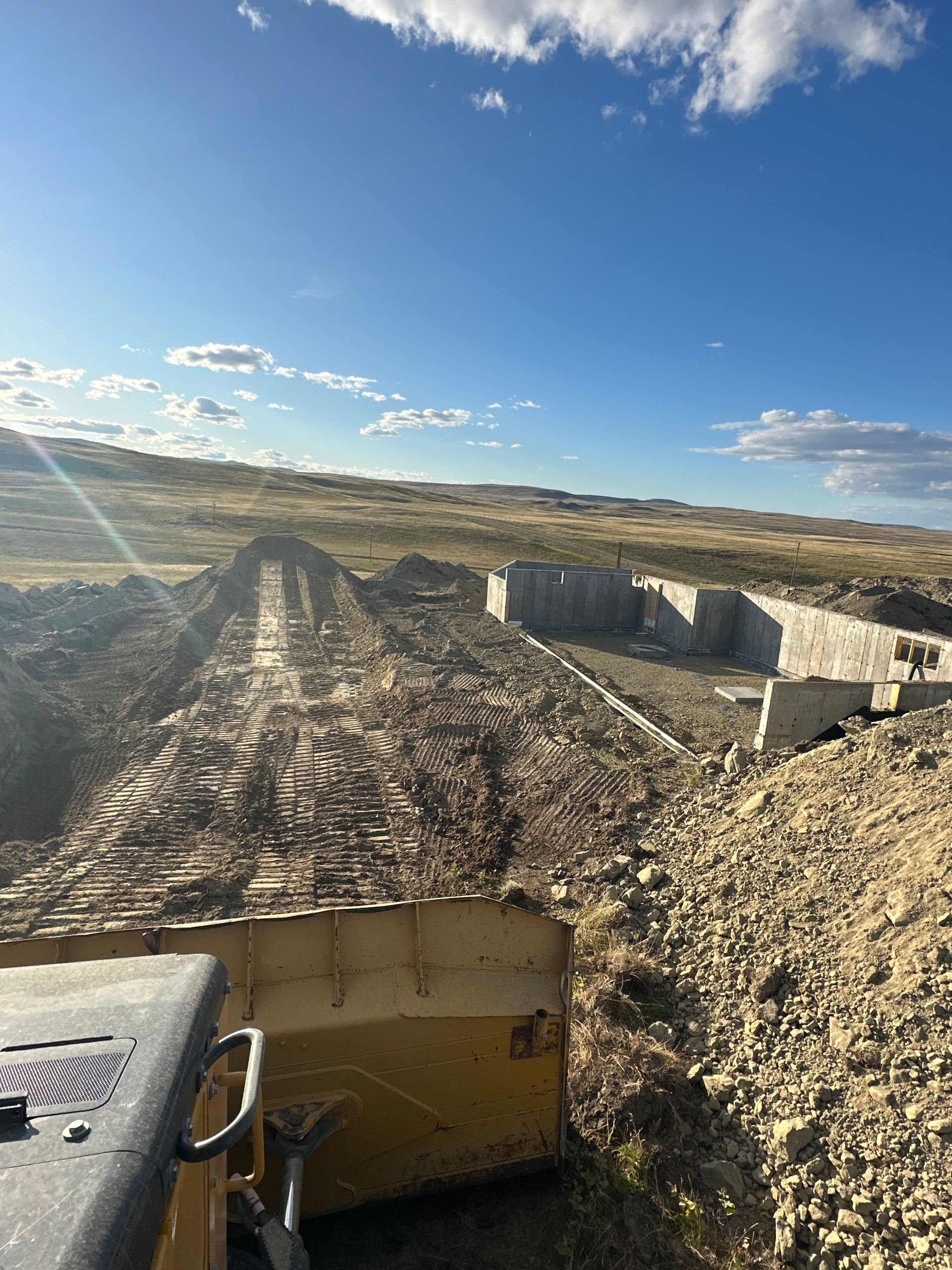 A bulldozer is driving down a dirt road in the desert.
