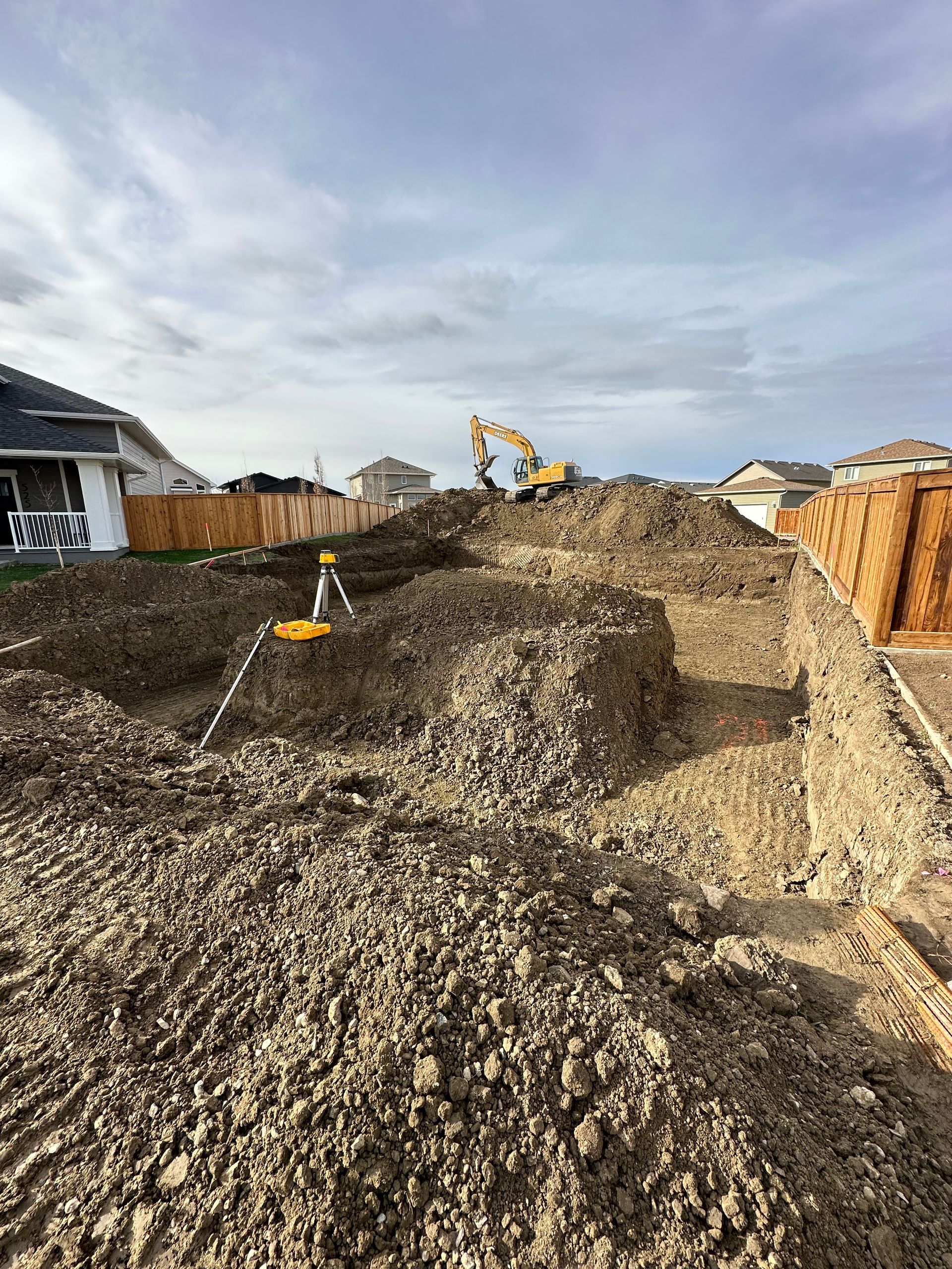 A construction site with a lot of dirt and a house in the background.