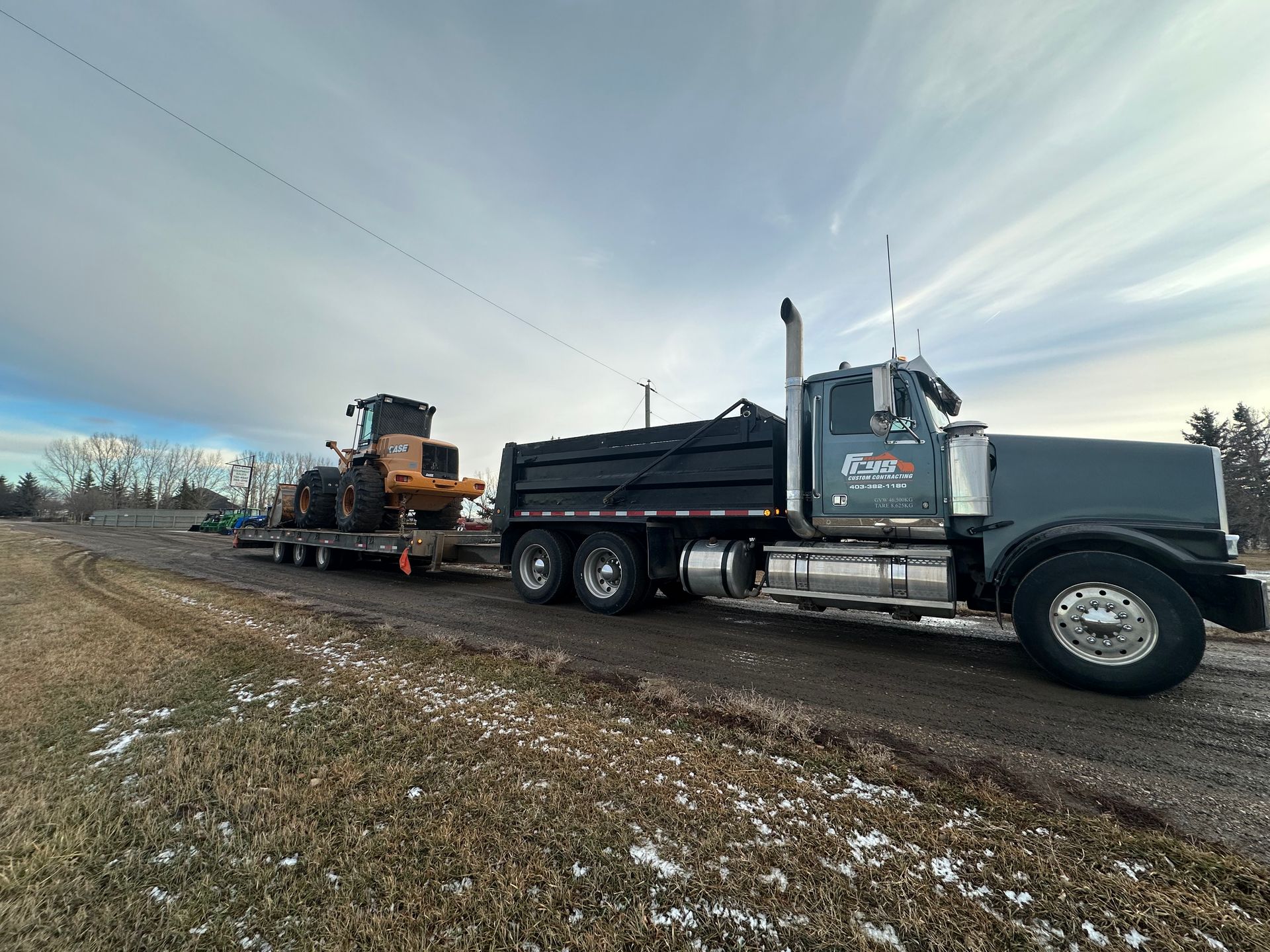 A dump truck is carrying a bulldozer on a trailer.